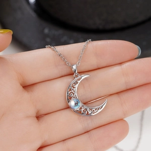Elegant filigree moon necklace with iridescent moonstone pendant held in hand