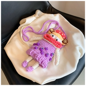 Detail view of handmade purple crochet doll bag with cute sausage mouth on silk cloth