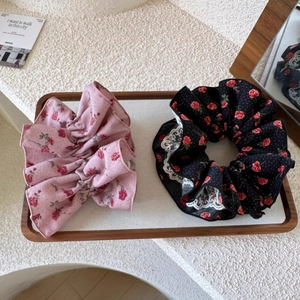 Détails de chouchous à fleurs roses et dentelle noire sur un plateau décoratif en bois