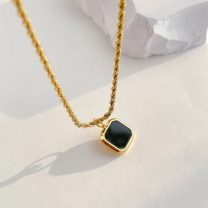 Detail of a vintage gold twist chain with a geometric black onyx square pendant
