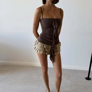 Dettaglio di canotta marrone scuro slim con volant e gonna a balze beige