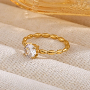 Macro shot of gold Mobius ring with sparkling zircon stone on a textured beige fabric
