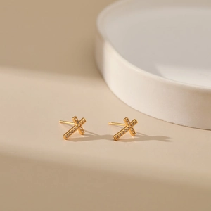 Minimalist 18K gold plated cross stud earrings with zircon stones on a beige tray