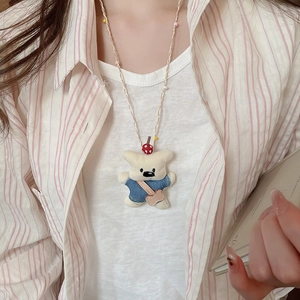 Detail of cute bear pendant with blue denim top and pink heart bag on woven chain