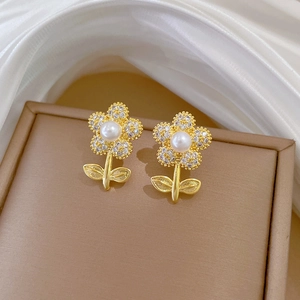 Macro detail of gold flower earrings with pearls and crystals on leather box