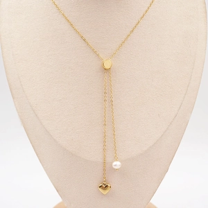 Elegant gold Y-shaped necklace with heart pendant and pearl on a beige jewelry bust