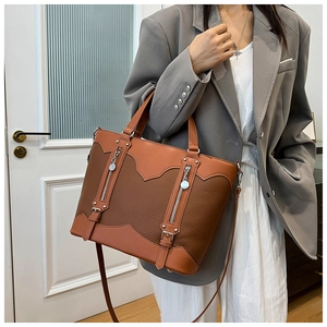 Detail of two-tone brown tote bag featuring lychee texture and dual metal zippers