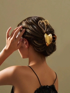 Close-up of elegant gold heart-shaped metal hair claw clip worn by a model