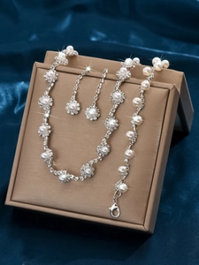 Luxurious bridal jewelry set with pearls and rhinestones displayed on a brown gift box
