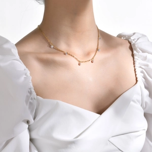Detail shot of a minimalist gold titanium steel necklace with clear zircon stones on a model