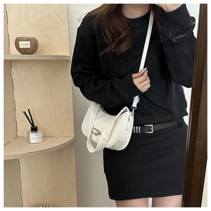 Close-up of white crescent shoulder bag with metallic D logo shown in a lifestyle mirror photo