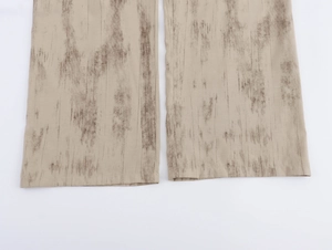 Dettaglio ravvicinato dell'orlo dei pantaloni casual beige con motivi marroni e trama del tessuto