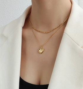 Détail du collier double couche doré avec pendentif cœur sur un mannequin en blanc