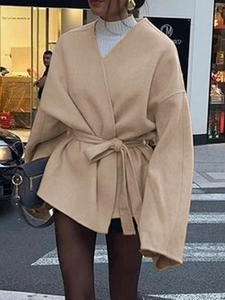 Détail du manteau en laine camel avec ceinture nouée, col en V et style urbain élégant