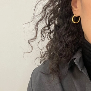 Close-up of gold twisted rope hoop earrings on a model showing minimalist style