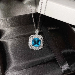 Detailed close-up of a square blue topaz pendant set in a luxury black silk jewelry box