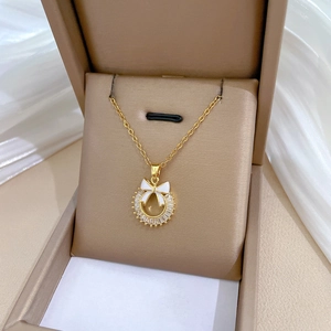 Detailed macro view of gold-plated titanium steel bow pendant with zircon and enamel inlay
