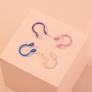 U-shaped faux nose rings in purple, blue, and gold colors on a soft matte display cube