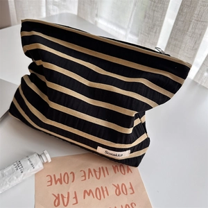 Detail of striped fabric cosmetic bag with Sozakka label and black zipper closure