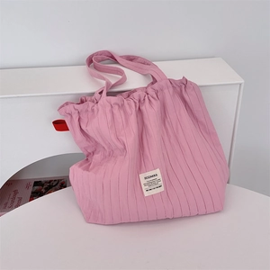 Detailed macro view of the pink pleated fabric texture and stitched brand label on the tote bag