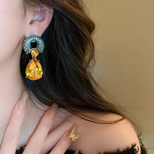 Detail of vintage teardrop earrings with emerald pavé ring and yellow faceted gem
