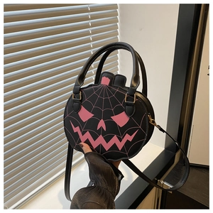 Detail of black pumpkin bag with pink embroidery, top handle, and adjustable strap