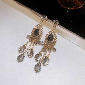 Close-up of bohemian style long tassel earrings with gray crystal teardrops and gold finish