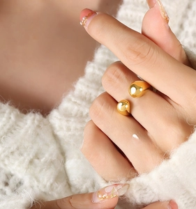 Detailed view of an 18k gold-plated geometric sphere ring on a model with knitwear