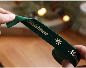 Detail of dark green velvet Christmas ribbon with gold stamped Merry Christmas text