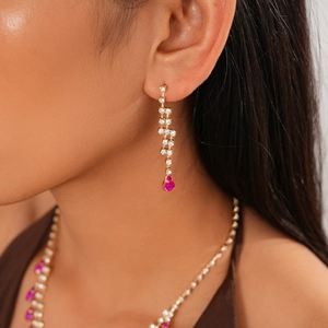 Detail of luxury gold jewelry set with rose red teardrop stones and sparkling crystals