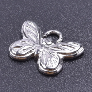 Macro detail of silver butterfly pendant with embossed wing texture on gray surface