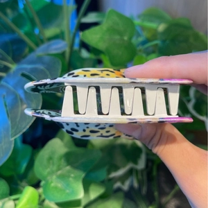 Detail of leopard print acrylic hair claw clip with yellow and black pattern and white teeth