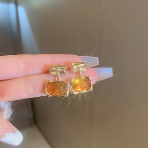 Close-up of vintage amber resin earrings with textured gold metal and square gemstone