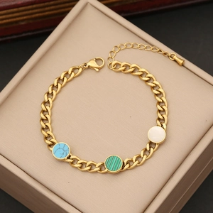 Detail of gold chain bracelet featuring blue marble, green, and white circular charms