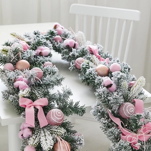 Illuminated white flocked Christmas garland with pink bows and ornaments for table decor