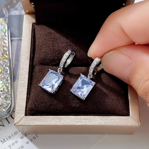 Close-up of rectangular purple and ice blue zircon drop earrings in a jewelry box