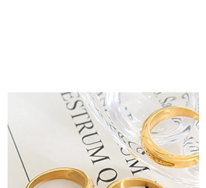 Macro shot of gold-plated textured twist rings on glassware with a book background
