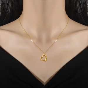 Golden heart pendant necklace in titanium steel worn by a model for a stylish look