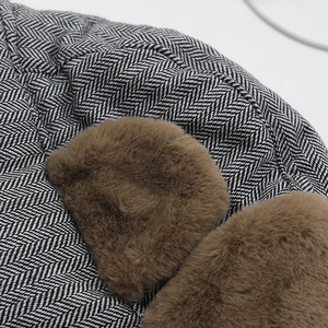 Macro detail of herringbone knit pattern and plush brown faux fur on winter trapper hat