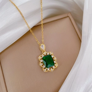 Collier en or avec pierre verte taille émeraude et diamants sur velours beige luxe