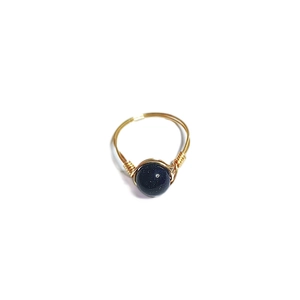 Detail of handcrafted gold wire wrapped ring featuring a deep blue sandstone bead