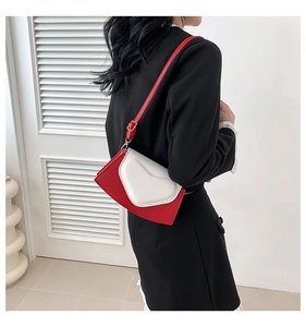 Détail du sac à bandoulière en forme de cœur bicolore rouge et blanc et boucle dorée