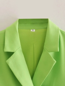 Detail of lime green blazer collar with size S label and premium fabric texture
