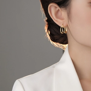 Nahaufnahme von dreilagigen goldenen geometrischen Ohrringen, getragen von einem Modell