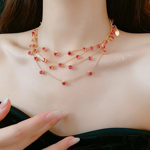 Gros plan d'un collier doré multi-rangs orné de pierres de zircon rouge élégantes