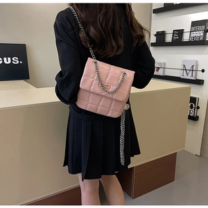 Detail of pink quilted square bag featuring silver heart clasp and metal chain strap