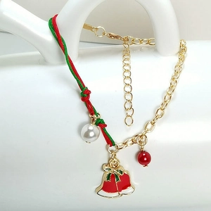 Detailed shot of Christmas bracelet with red and green braided rope, pearls and bells