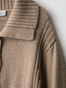 Detail of tan knit cardigan showing ribbed lapel collar and chunky sweater texture