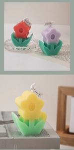 Close-up of tulip-shaped scented candles in red, purple, and yellow on a book