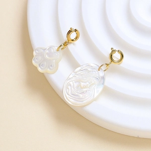 Detail of white shell cat paw and relief portrait charms with golden spring buckles